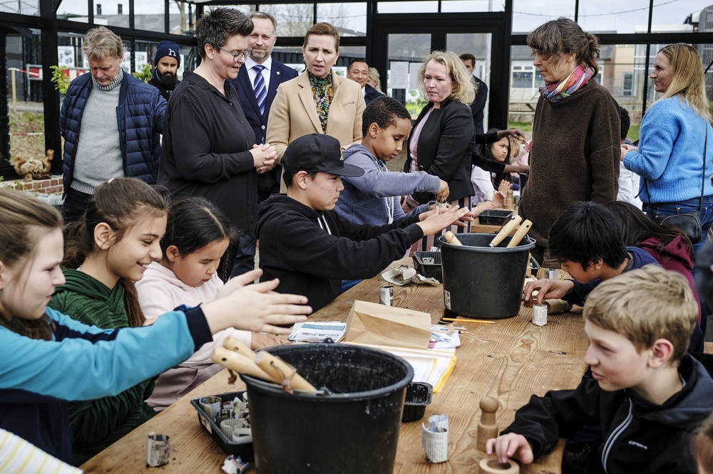 Frederiksen (beige jas) bezoekt een school waar Deense kinderen en Oekraïense vluchtelingen kinderen samen les krijgen, 7 april 2022